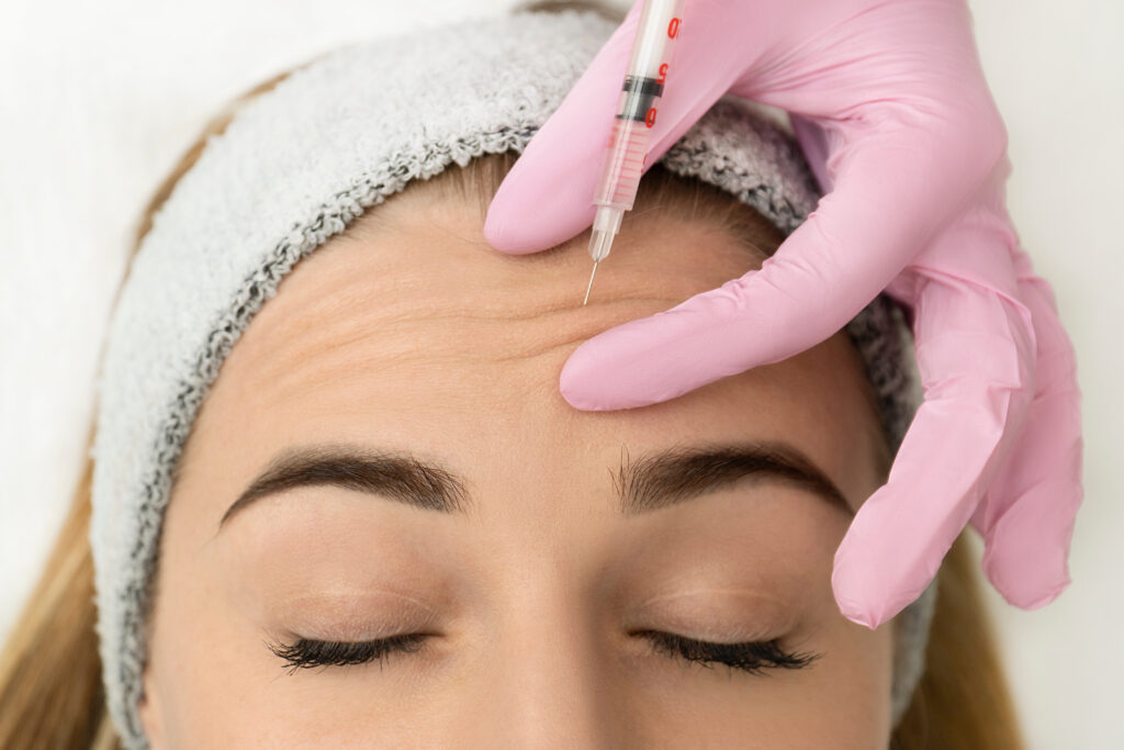 Close-up of the hands of an expert cosmetologist injecting botox into a womans forehead Correction of forehead and eye wrinkles with botulinum toxin › Hellenic Laser Spa