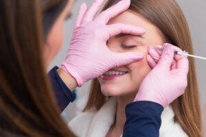 Woman wearing bathrobe in beauty clinic aesthetics patient cosmetic procedures botox application anti wrinkle and anti aging › Hellenic Laser Spa Patient receiving Botox treatment to reduce fine lines and achieve a youthful appearance.