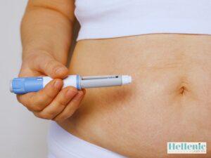Weight Loss Injection 2 › Hellenic Laser Spa Person administering a weight loss injection with a blue and white injection pen into the abdomen as part of a medically supervised weight management program.